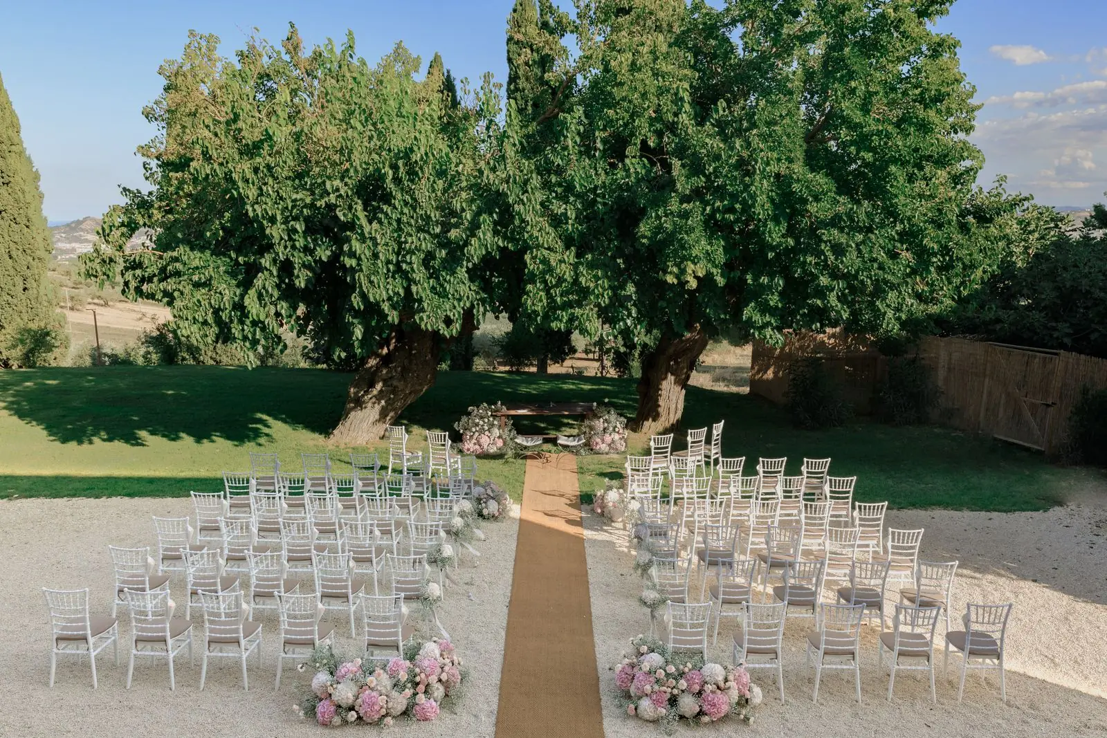 Ceremonia de boda preparada en el césped de un jardín con árboles grandes, finca bonita para bodas en Madrid