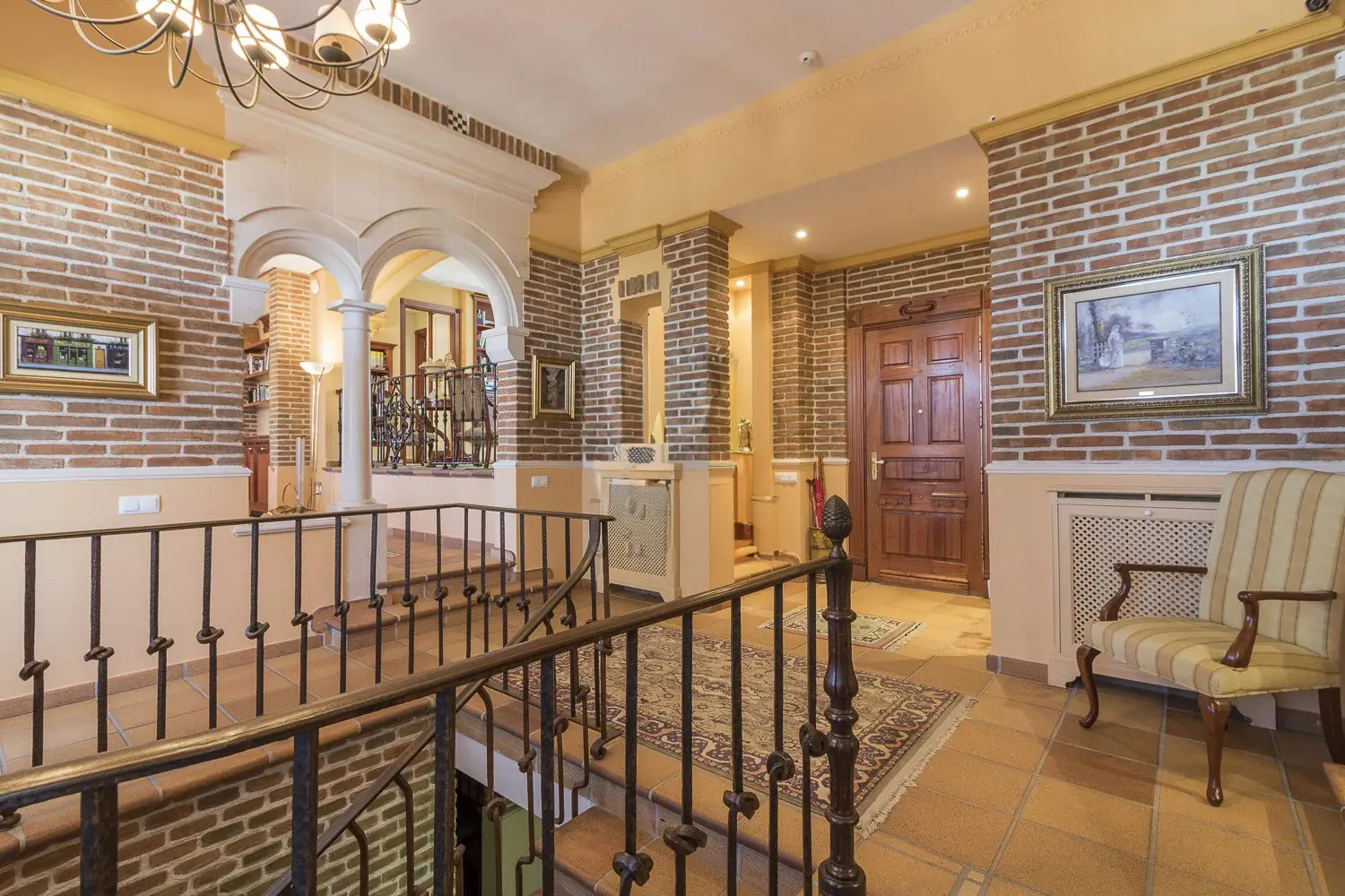 Distribuidor con ladrillo visto, arcos y escalera en Quinta de Serena